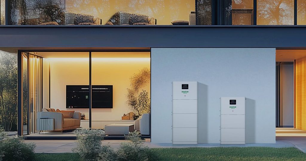 Batteries de stockage d'énergie EGSmart de deux tailles installées contre le mur d'une maison, le soir